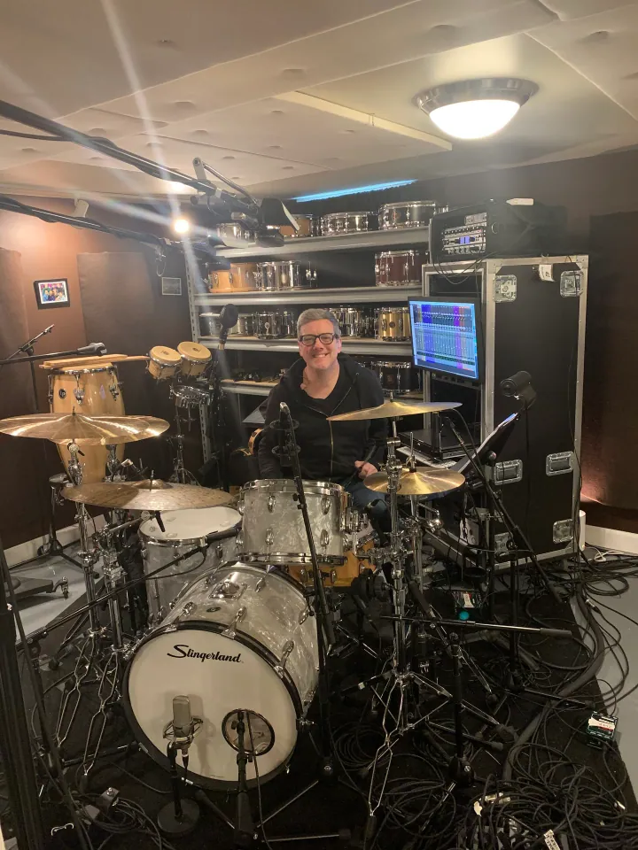 Paul Eckberg seated behind a drum kit in the studio.
