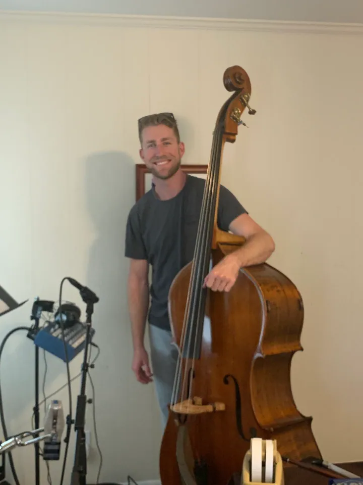 Erik Coveney playing an upright bass beside a studio microphone.