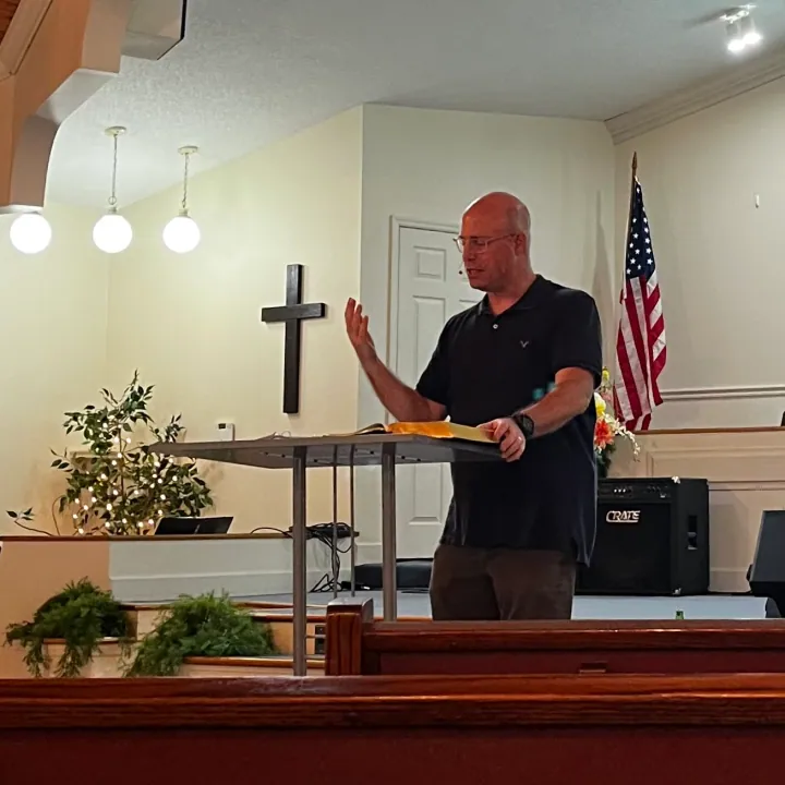 Sam preaching from a church pulpit.