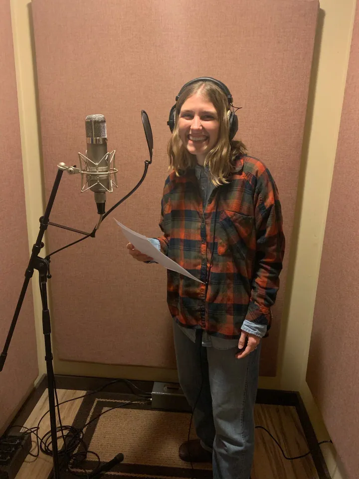 Ellie Turner standing at a microphone in the vocal booth.